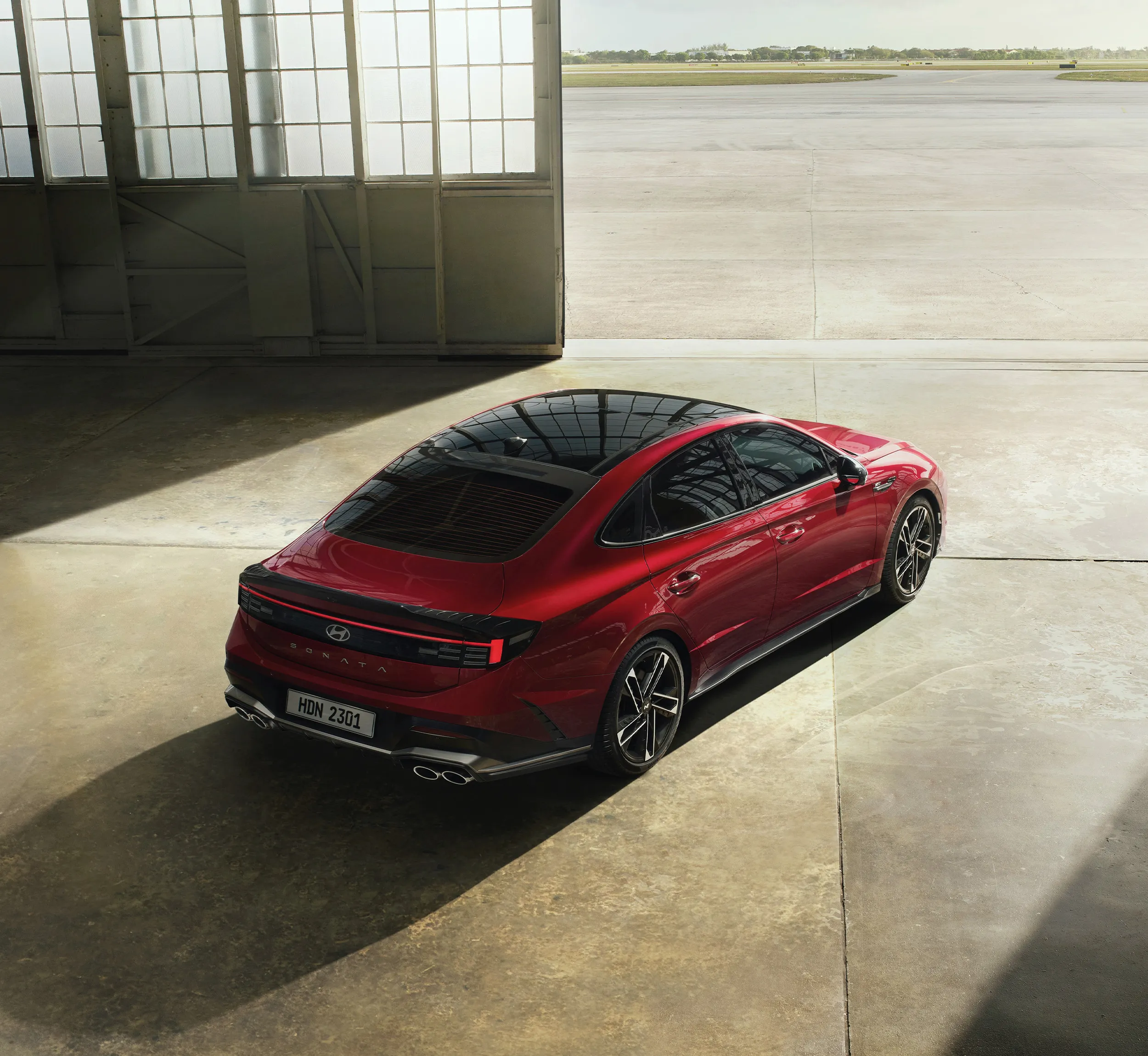 Rear bumper of a red fastback sedan in a hangar