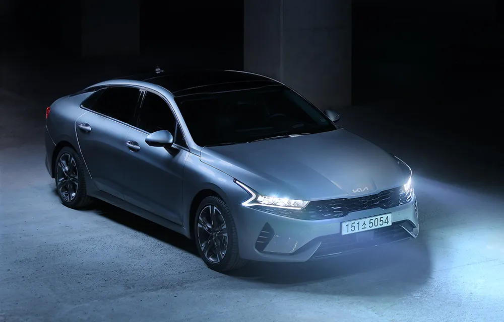 Silver sedan in a dark garage with headlights on
